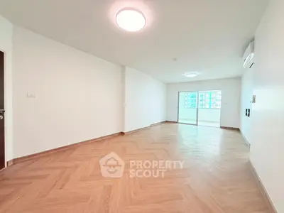 Spacious empty living room with wooden flooring and balcony access