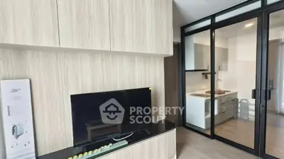 Modern living room with sleek TV setup and glass partition to kitchen