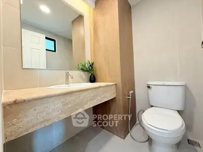 Modern bathroom with sleek fixtures and elegant design, featuring a spacious countertop and contemporary toilet.
