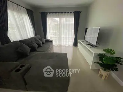 Spacious living room with modern sofa and large TV, perfect for relaxation.