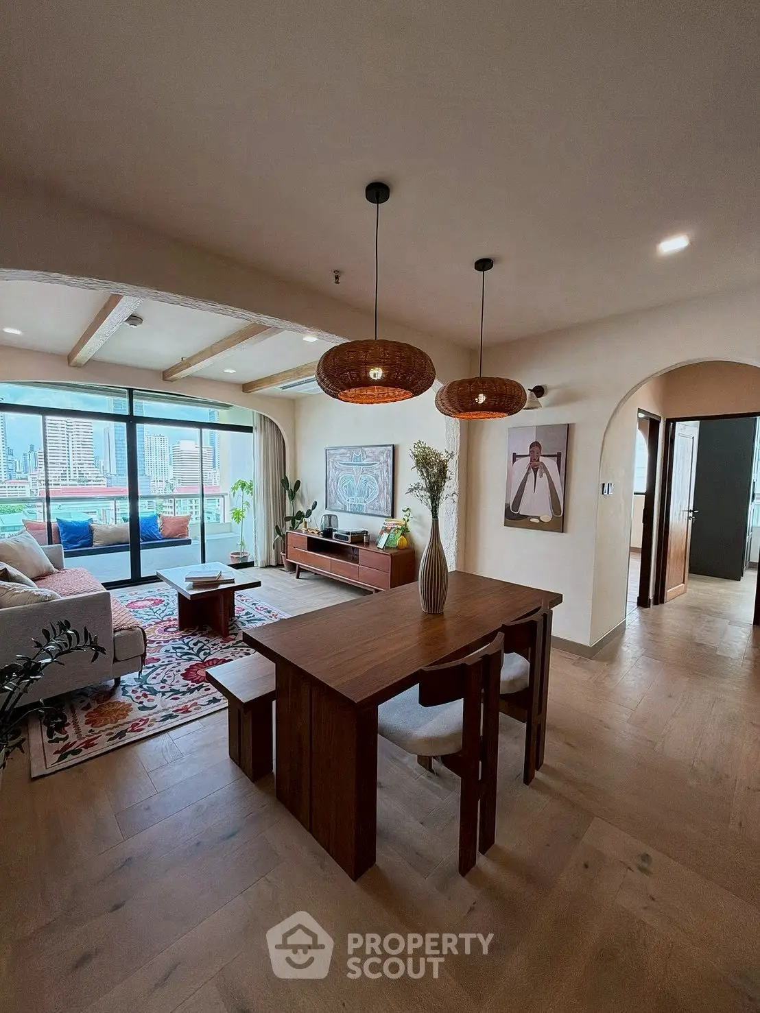 Spacious living room with modern decor and stunning city view, featuring elegant wooden furniture and stylish lighting.