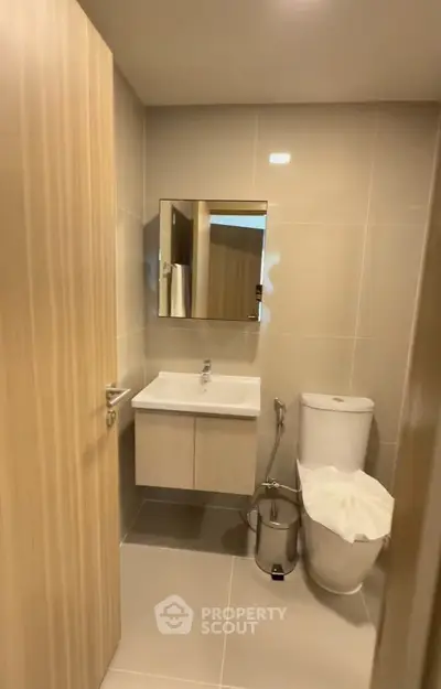 Modern bathroom with sleek fixtures and neutral tones, featuring a wall-mounted sink and contemporary toilet.