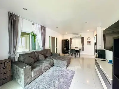 Spacious modern living room with plush gray sofa and dining area, perfect for relaxation and entertaining.
