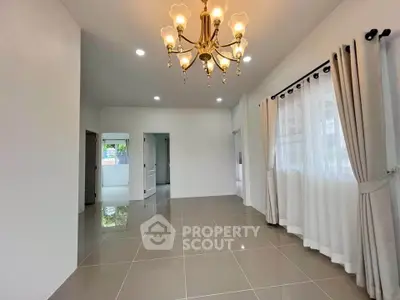 Spacious living room with elegant chandelier and large windows for natural light.