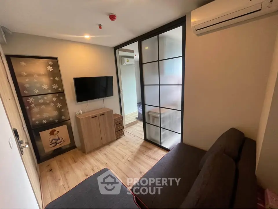 Modern living room with wooden flooring, stylish decor, and air conditioning in a cozy apartment.