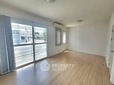 Spacious empty room with large windows and wooden flooring, perfect for customization.