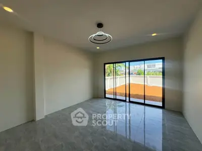 Spacious empty room with modern lighting and large sliding glass doors opening to a patio.