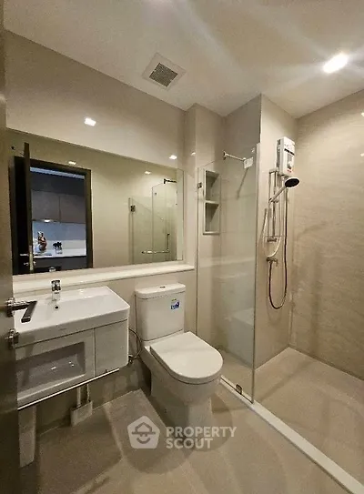 Modern bathroom with sleek fixtures and glass shower enclosure in a contemporary apartment.