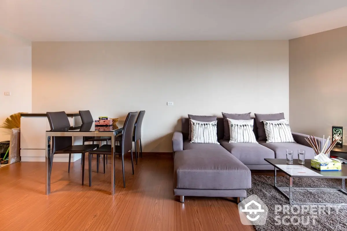 Spacious and modern living room with elegant sectional sofa, sleek dining set, and warm wooden flooring, perfect for entertaining and relaxation.