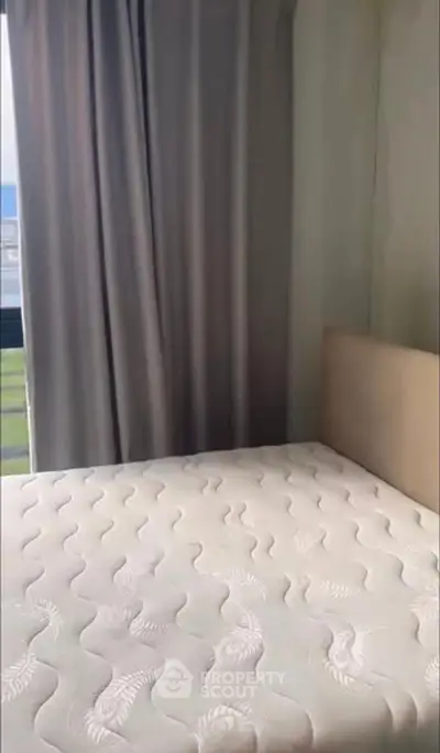 Cozy bedroom with a comfortable mattress and large window offering natural light.