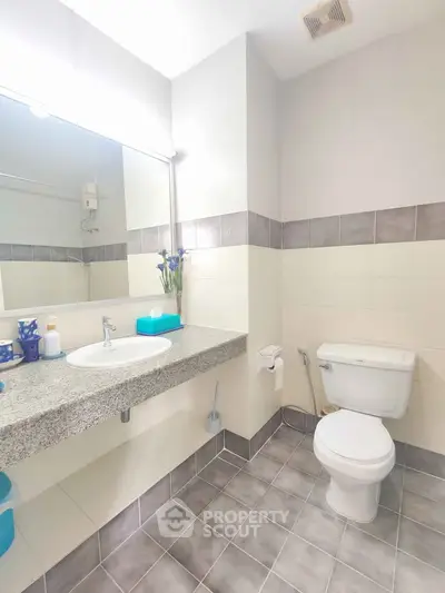 Modern bathroom with sleek design, featuring a granite countertop and stylish tile flooring.