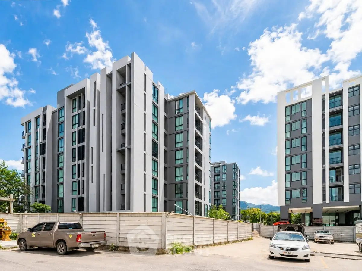 Modern apartment complex with sleek design and ample parking under a clear blue sky.
