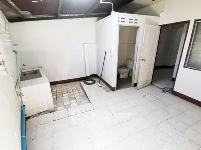 Spacious utility room with sink and tiled floor, ideal for laundry or storage.