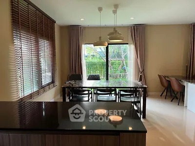 Elegant dining area with large windows and modern lighting, offering a serene garden view.