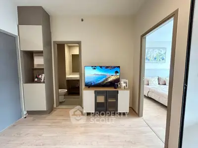 Modern living room with TV and view into cozy bedroom, showcasing open layout and stylish decor.