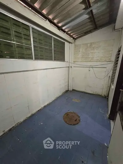 Spacious storage area with blue tiled floor and metal roof, ideal for versatile use.