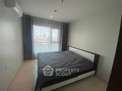 Spacious bedroom with large window and modern furnishings in a bright apartment.