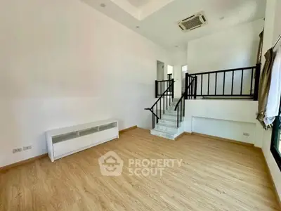 Spacious living room with wooden flooring and modern staircase, perfect for stylish living.