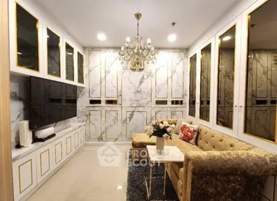 Luxurious living room with elegant chandelier and marble accents, featuring plush seating and modern entertainment setup.