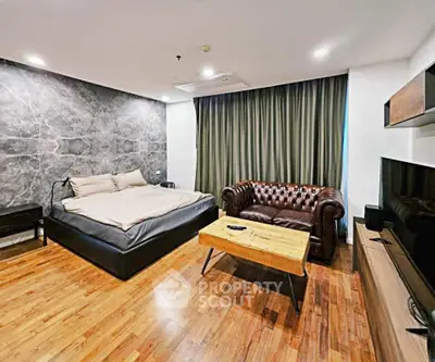 Spacious bedroom with modern decor, featuring a luxurious leather sofa and stylish wooden flooring.