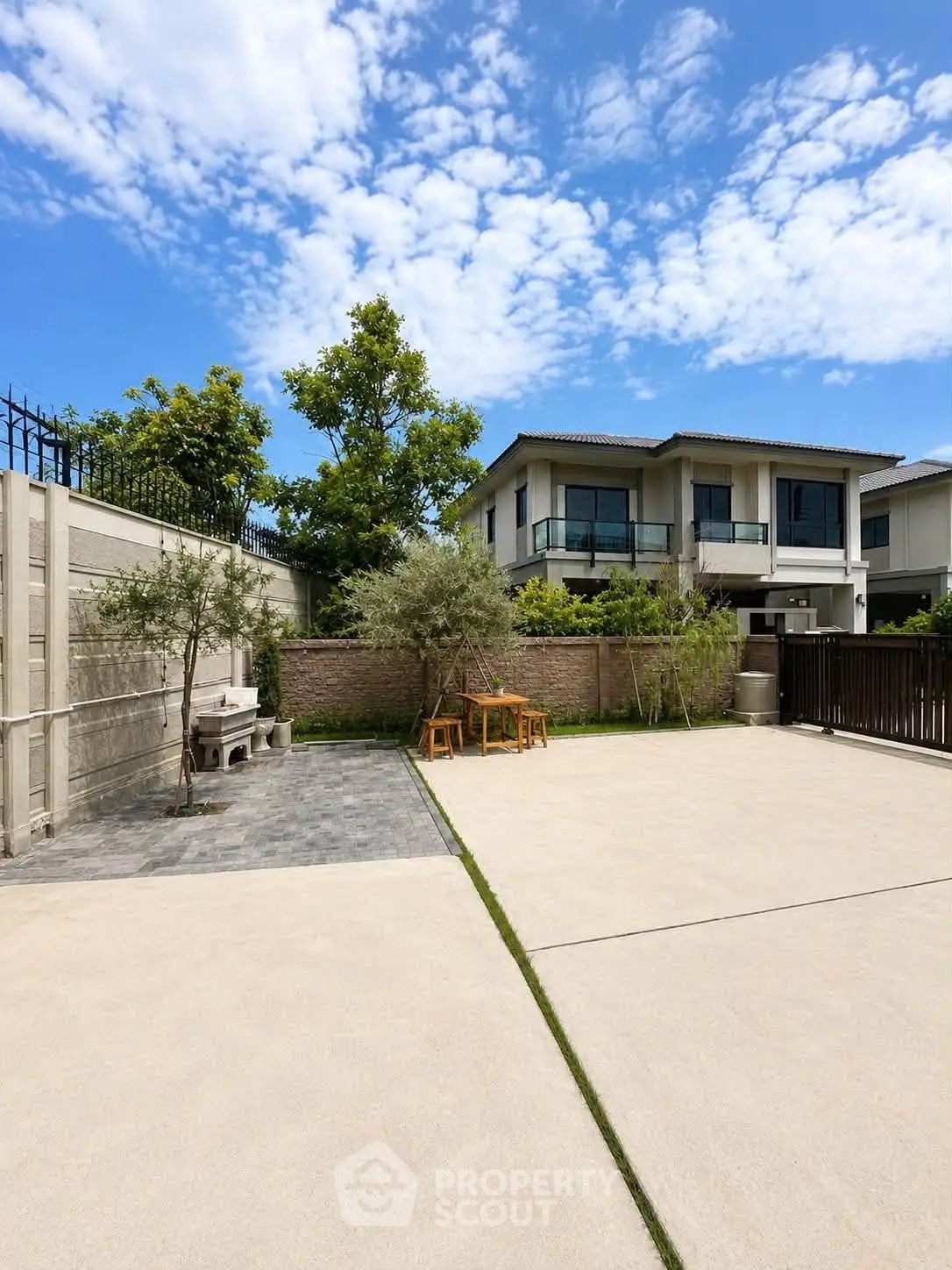 Spacious modern home with large driveway and lush greenery under a clear blue sky.