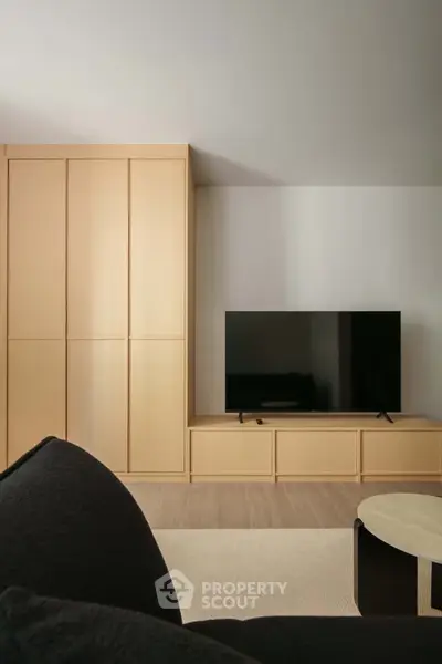 Modern living room with sleek TV setup and stylish wooden cabinetry.