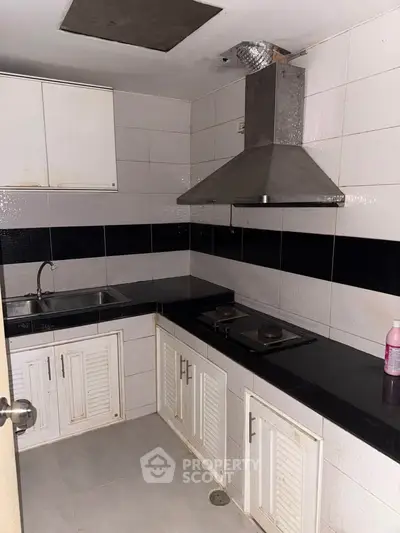 Compact kitchen with black countertops and modern range hood