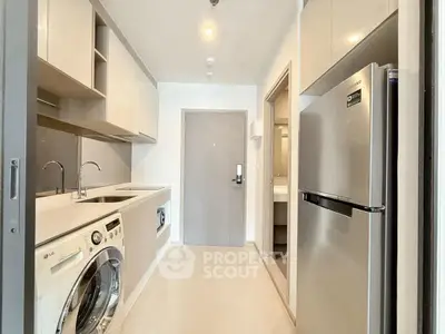 Modern kitchen with sleek appliances and washing machine in compact layout.