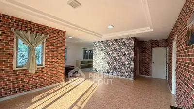 Spacious living room with brick walls and floral accent wall, ample natural light.