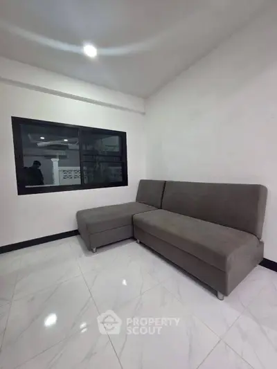 Modern living room with sleek gray sofa and large window, perfect for relaxation.