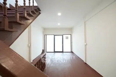 Spacious interior with wooden staircase and large windows, perfect for natural light.