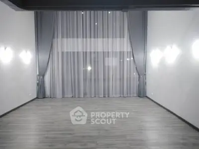 Spacious empty room with elegant floor-to-ceiling curtains and modern lighting