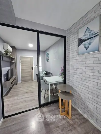 Modern living room with stylish decor and glass partition, featuring sleek furniture and wood flooring.