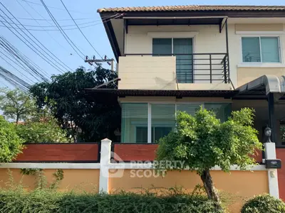 Charming two-story house with balcony and lush greenery in a serene neighborhood.