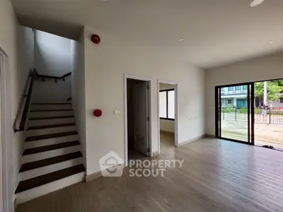 Spacious modern interior with wooden flooring and large windows, ideal for natural light.