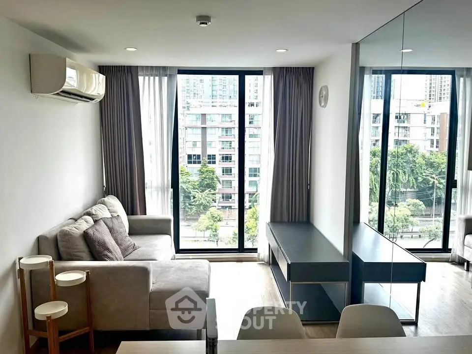 Modern living room with large windows and city view, featuring cozy sofa and sleek furniture.
