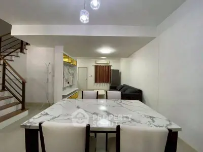 Modern dining area with marble table and elegant lighting in a spacious open-plan living room.