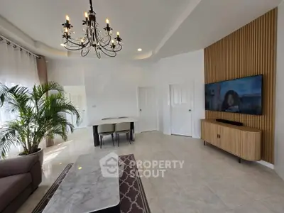 Elegant living room with chandelier, modern TV setup, and stylish dining area