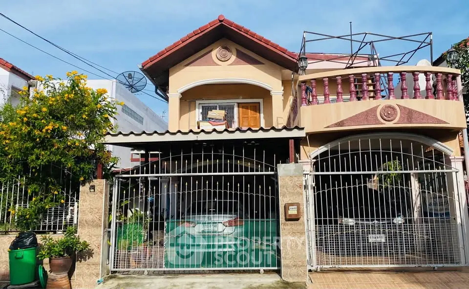 Charming two-story house with gated driveway and balcony in a suburban neighborhood.