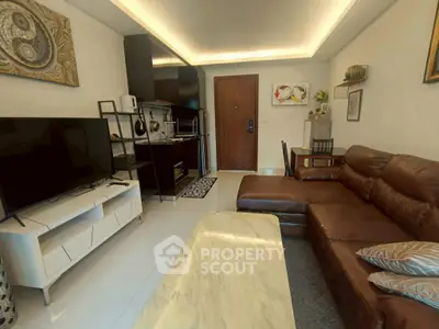 Modern living room with leather sofa, TV, and open kitchen layout in stylish apartment.