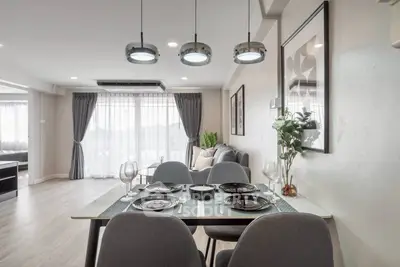 Modern dining area with elegant table setting and stylish lighting in open-plan living space.