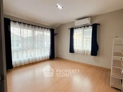 Spacious empty room with large windows and wooden flooring, perfect for customization.