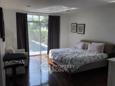 Bright bedroom with pool view, featuring elegant decor and natural light.