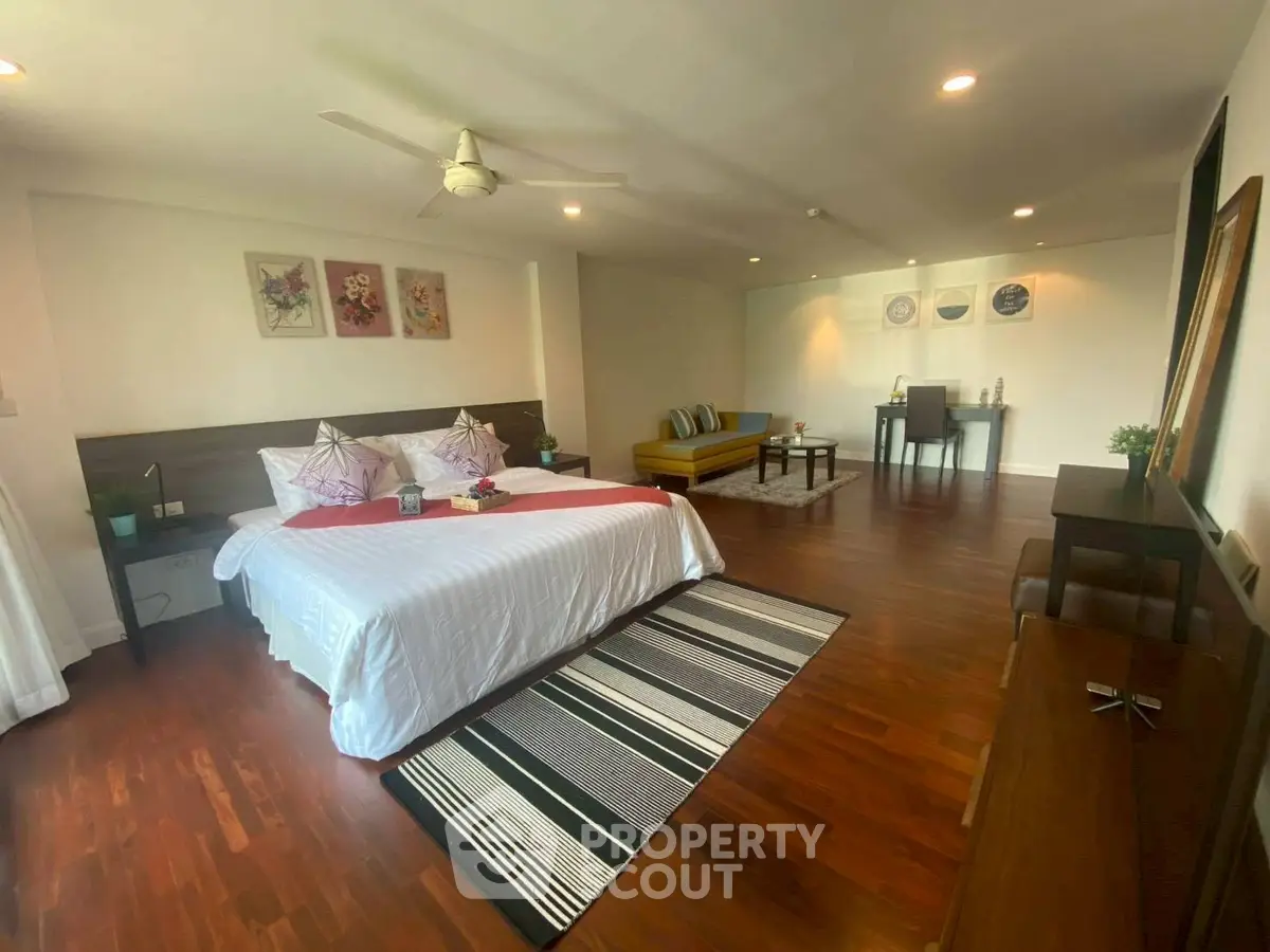 Spacious bedroom with elegant decor and hardwood floors in a modern apartment.