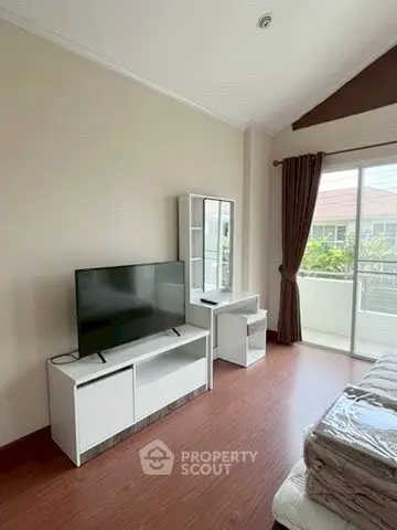 Spacious bedroom with modern TV setup and balcony access