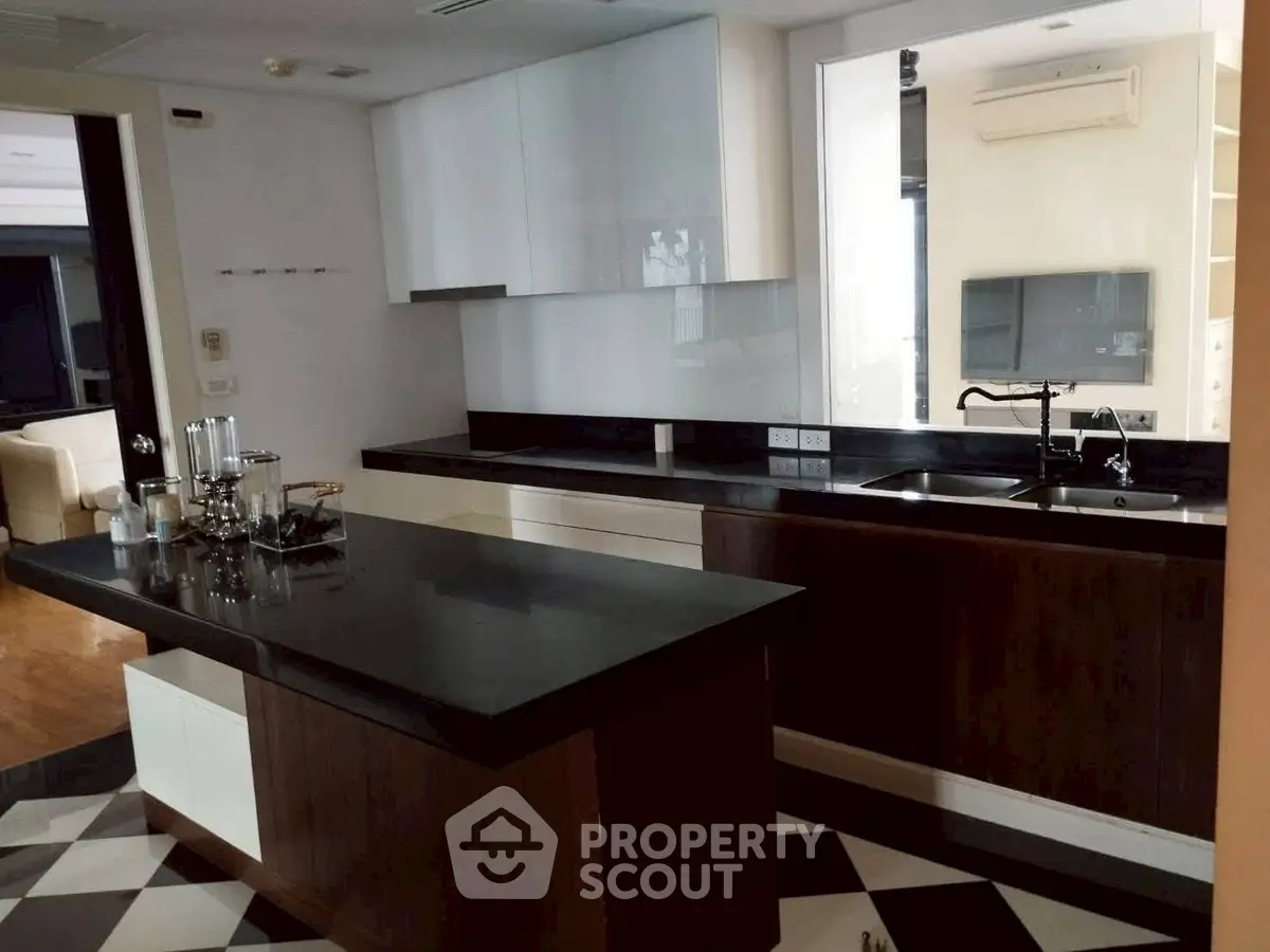 Modern kitchen with sleek black countertops and island in contemporary apartment.