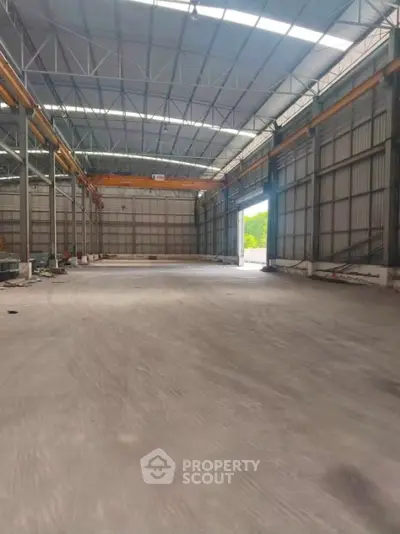 Spacious industrial warehouse with high ceilings and ample natural light, perfect for storage or manufacturing.