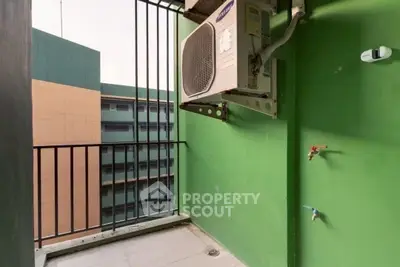 Compact balcony with air conditioning unit and urban view, ideal for city living.