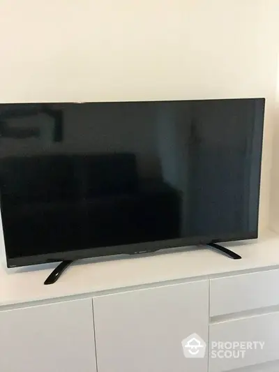 Modern living room with sleek flat-screen TV on white cabinet