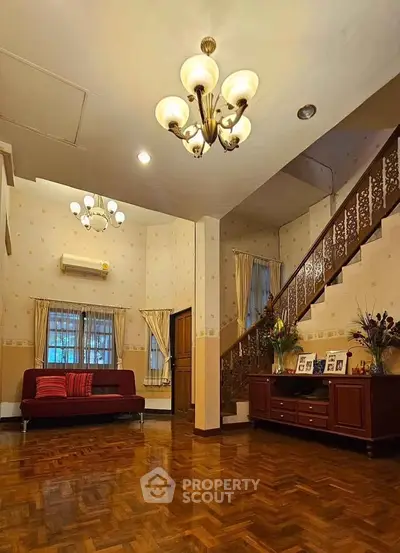 Spacious living room with elegant chandelier and wooden staircase